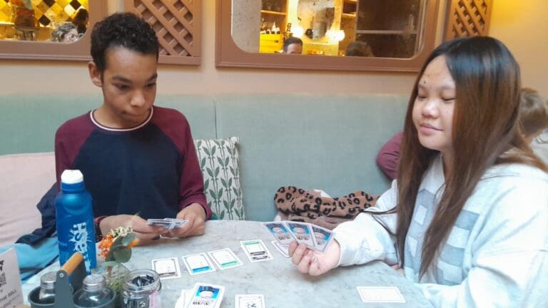 Photo of 2 people sitting playing a card game