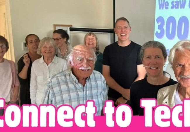 A group of older adults smiles in a classroom with a projector screen reading We saw our 3,000 Attendances. Text over the image says Connect to Tech in bold pink and white letters, celebrating this inspiring tech event.